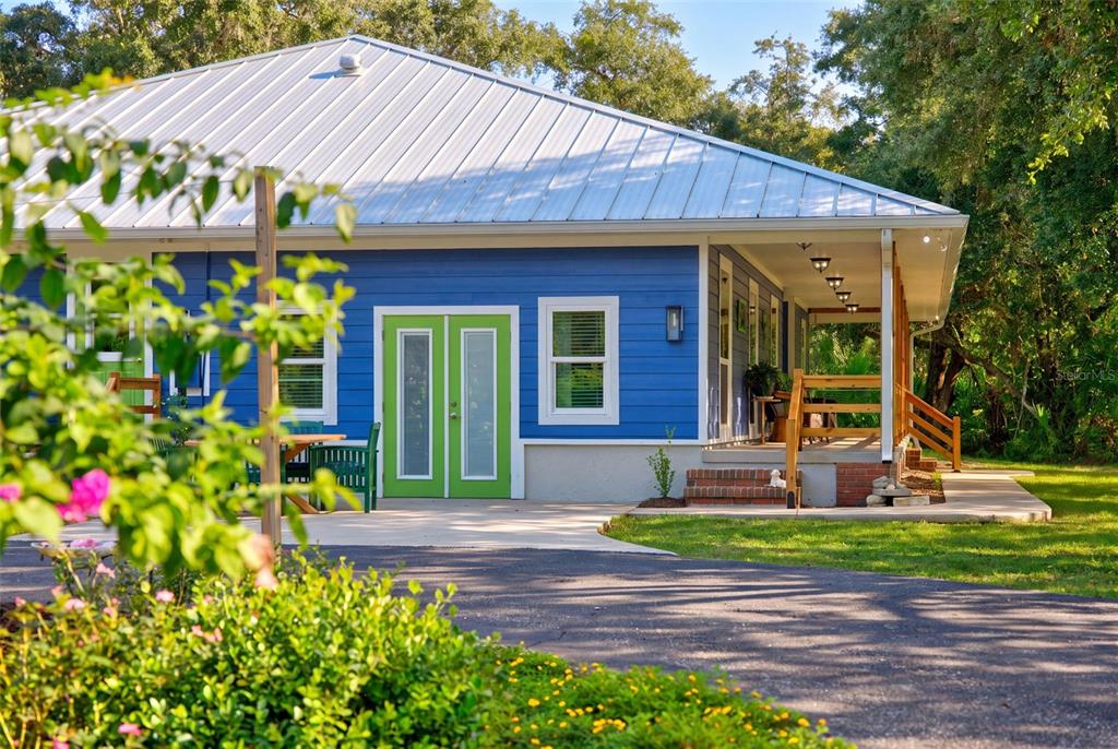 A covered porch features blue siding, wicker chairs, potted plants, and a small wooden table — 9990 SW COUNTY ROAD 769, ARCADIA, FL