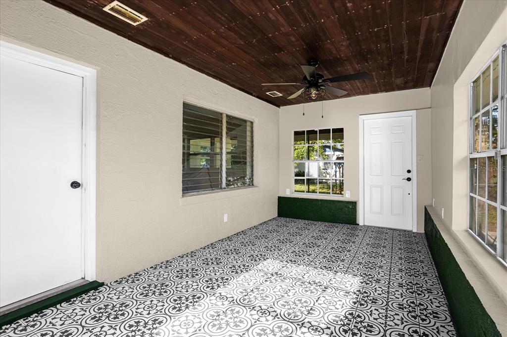 A sunroom features patterned tile flooring, a dark wood-paneled ceiling, and a ceiling fan — 1008 10TH STREET, DAYTONA BEACH, FL