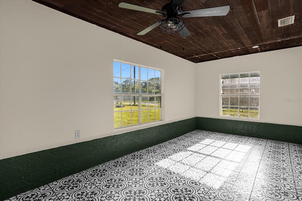 A room features a dark wood plank ceiling, patterned tile floors, and green wainscoting — 1008 10TH STREET, DAYTONA BEACH, FL