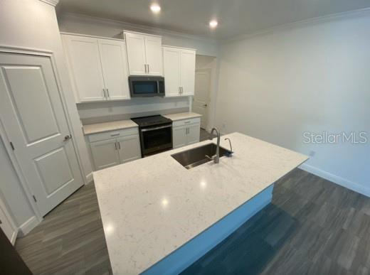 A kitchen features white cabinets, a central island with a sink, and light-colored countertops — 9967 RED BAY LOOP, LAND O LAKES, FL