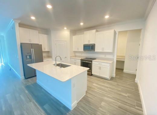 A modern kitchen features white cabinetry, stainless steel appliances, and a central island with quartz — 9967 RED BAY LOOP, LAND O LAKES, FL