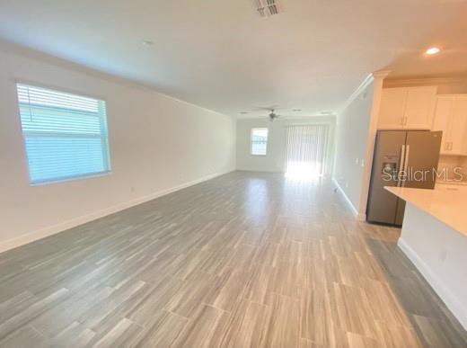 An open-concept living area features light wood-look tile flooring and a view of the kitchen — 9967 RED BAY LOOP, LAND O LAKES, FL