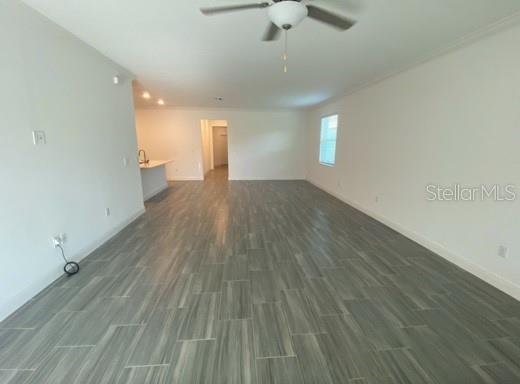 An open-concept living area features light walls, a ceiling fan, and gray wood-look tile flooring — 9967 RED BAY LOOP, LAND O LAKES, FL