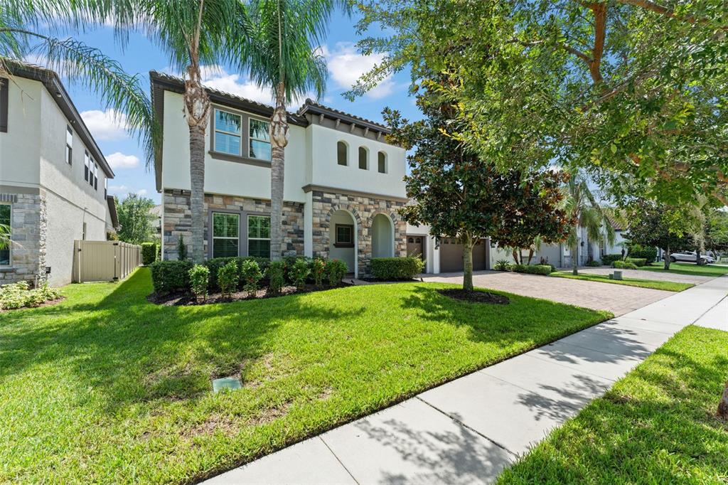 A two-story house with a stone facade, palm trees, and a paved driveway — 8498 MOREHOUSE DRIVE, ORLANDO, FL