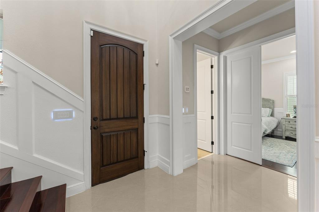 An entryway with a dark wood door, white wainscoting, and tile flooring — 8498 MOREHOUSE DRIVE, ORLANDO, FL
