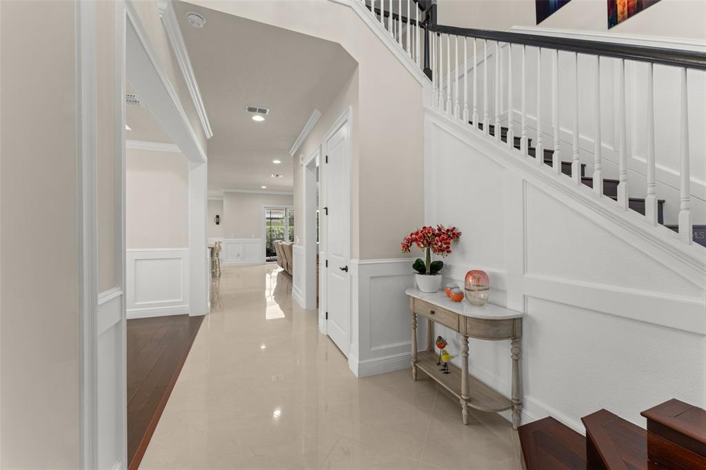 A bright foyer features a staircase with dark wood treads and white wainscoting walls — 8498 MOREHOUSE DRIVE, ORLANDO, FL