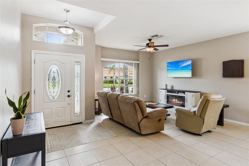 A living room features a sofa, recliner, coffee table, fireplace console, and a wall-mounted television — 1742 ALTAVISTA CIRCLE CIRCLE, LAKELAND, FL