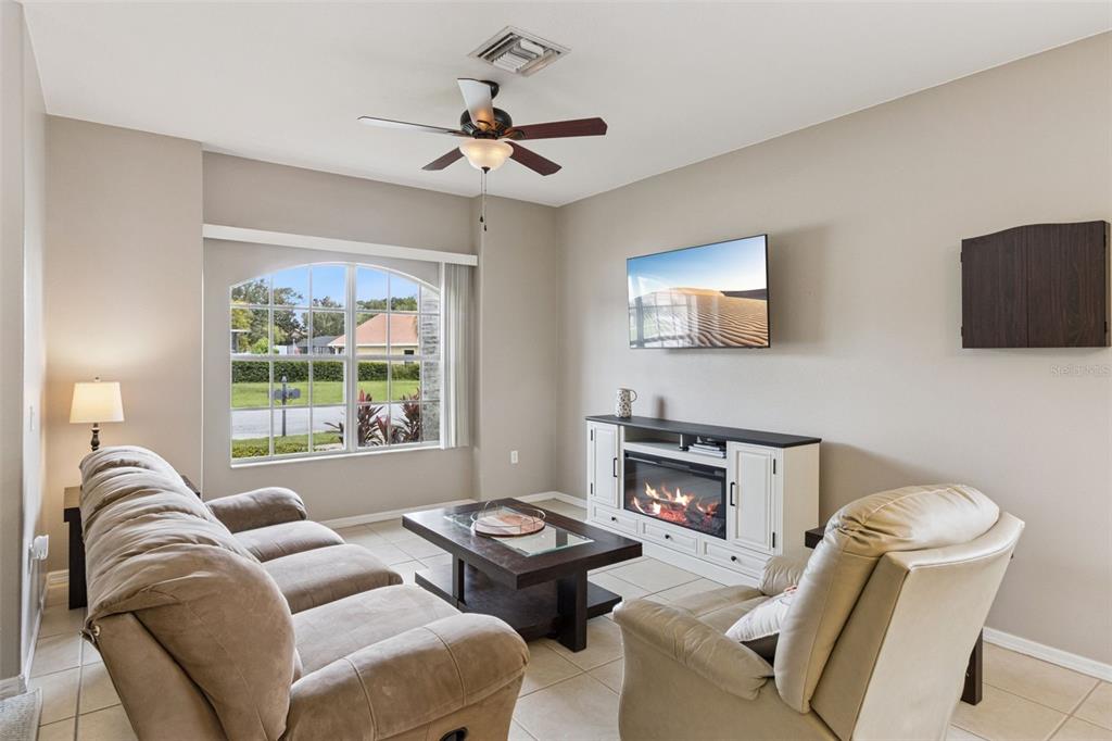 An open-concept living and dining area features tile flooring, a fireplace, and neutral walls — 1742 ALTAVISTA CIRCLE CIRCLE, LAKELAND, FL