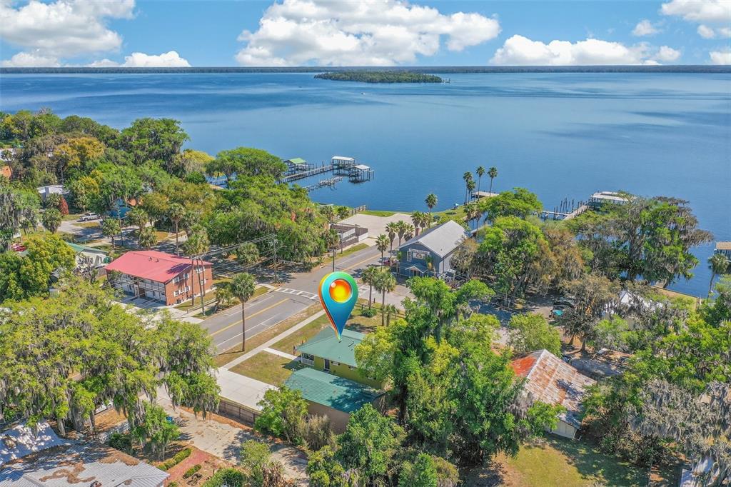 An aerial view shows a green house with a metal roof near a large lake — 105 CENTRAL AVENUE, CRESCENT CITY, FL