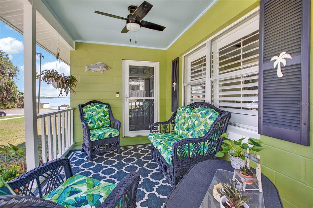 A covered porch with lime green walls, wicker furniture, and a view of the water — 105 CENTRAL AVENUE, CRESCENT CITY, FL