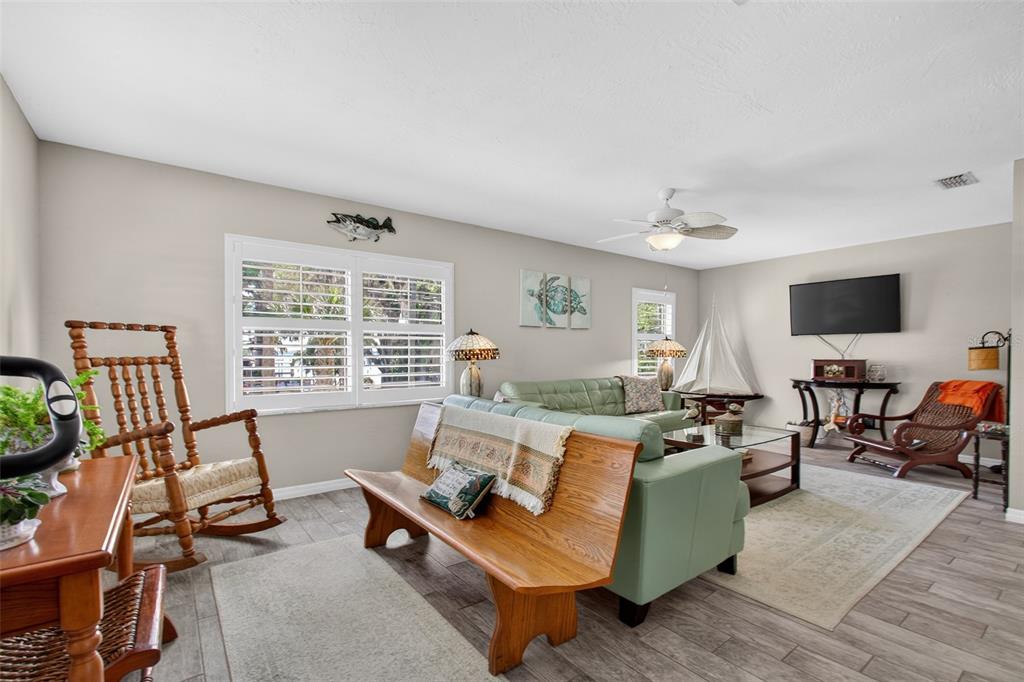 A living room features a green sofa, wooden bench, rocking chair, and a wall-mounted television — 105 CENTRAL AVENUE, CRESCENT CITY, FL