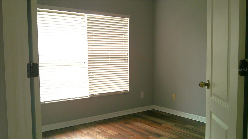 An empty bedroom features light gray walls, wood-look flooring, and a window with white blinds — 5718 FISHHAWK RIDGE DRIVE, LITHIA, FL