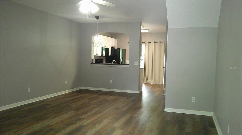 A living room with gray walls, wood-look flooring, and an open pass-through to the kitchen — 5718 FISHHAWK RIDGE DRIVE, LITHIA, FL