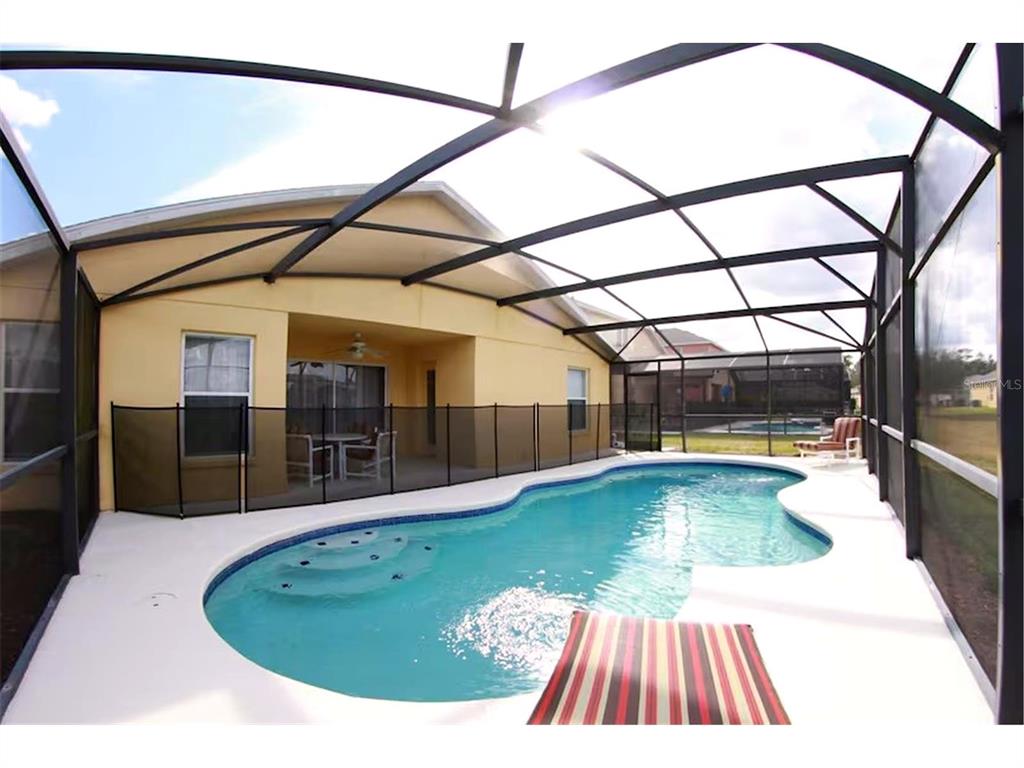 A screened-in patio features a swimming pool with steps and a black safety fence — 136 STARBIRD COURT, DAVENPORT, FL