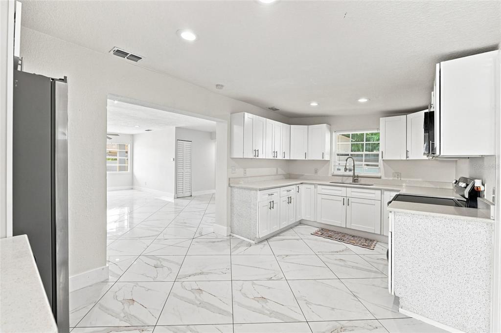 A kitchen with white cabinets, light countertops, and white marble-patterned tile flooring — 7805 WINSTON LANE, TAMPA, FL