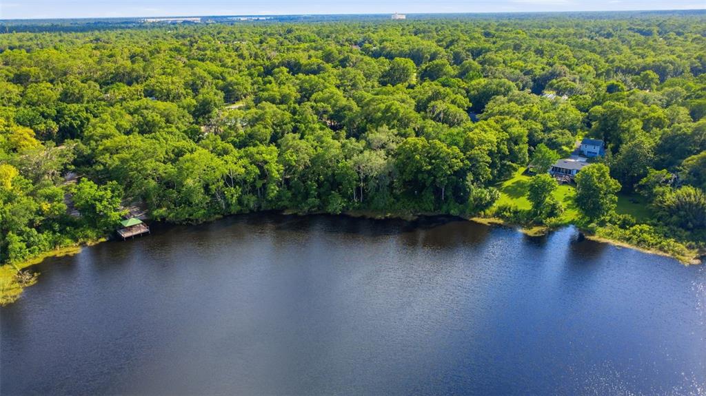 A wooden dock with a covered gazebo extends into a lake surrounded by lush trees — VISTA STREET, LAKE HELEN, FL
