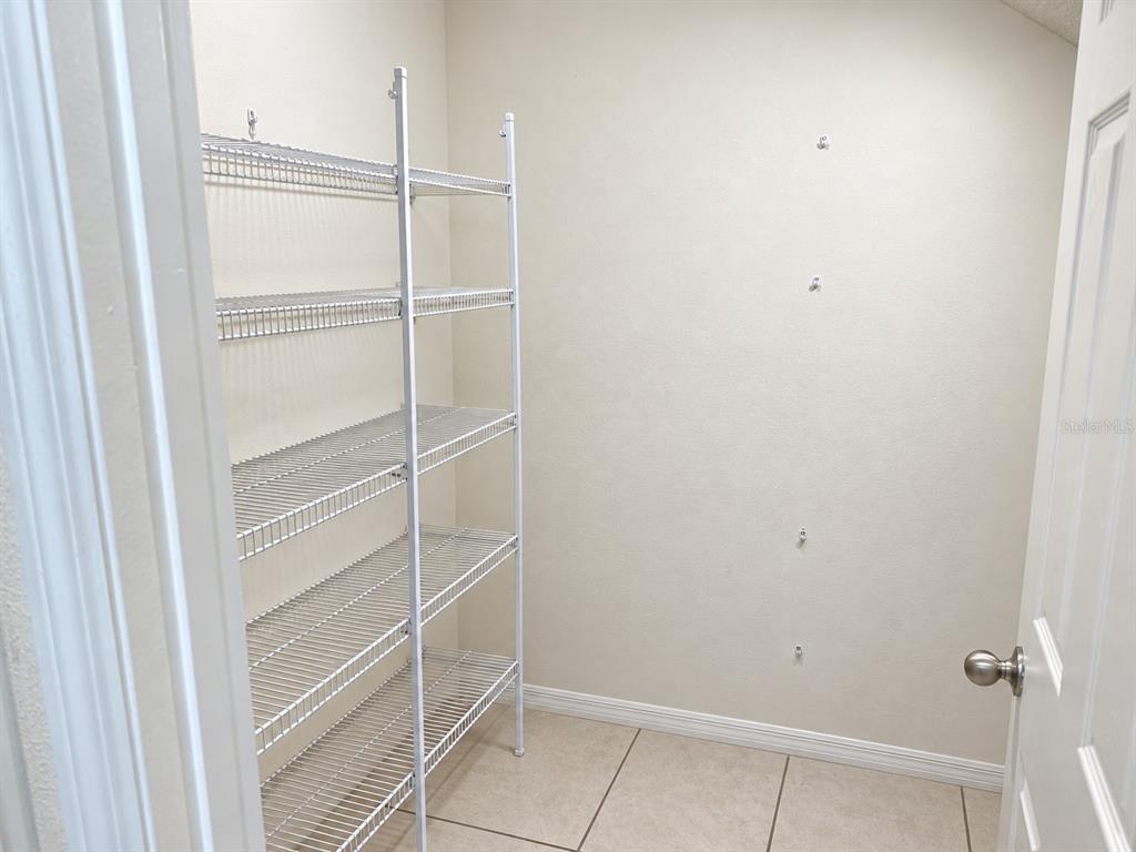 A small closet features white wire shelving and light-colored tile flooring — 2924 CREST DRIVE, KISSIMMEE, FL