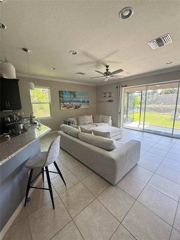 A living room with tile floors, a sectional sofa, and sliding doors leading to a yard — 6145 ANISE DRIVE, SARASOTA, FL