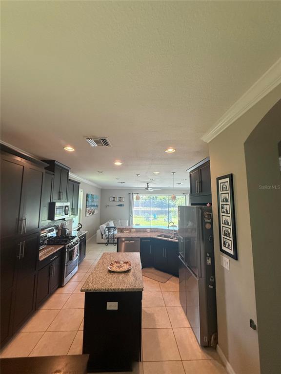 A kitchen with dark cabinetry, granite countertops, a center island, and a view of water — 6145 ANISE DRIVE, SARASOTA, FL