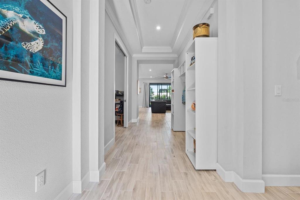 A hallway with light wood-look tile flooring leads toward an open living area — 4512 CRESTPOINT WAY, PALMETTO, FL