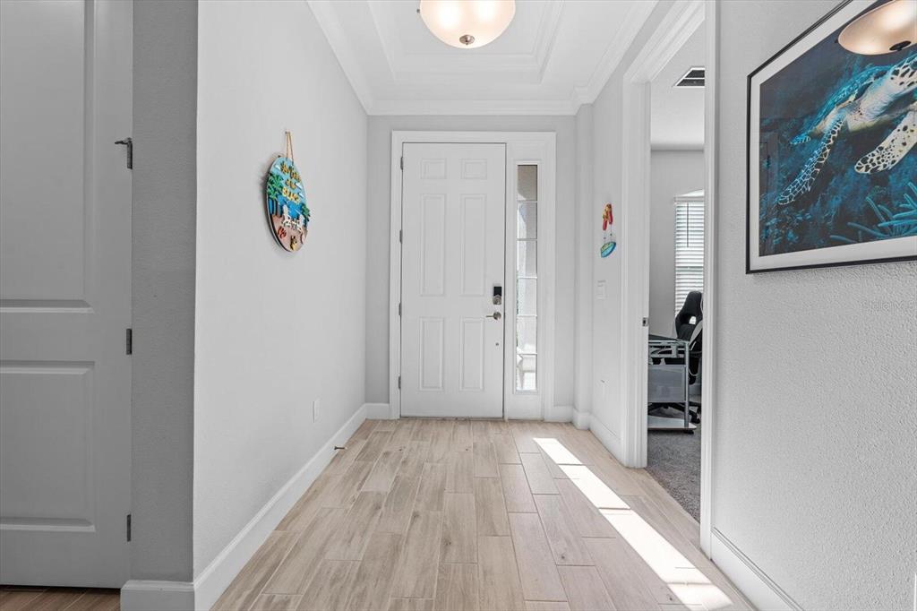 A bright entryway features light wood-look tile flooring, a white front door, and gray walls — 4512 CRESTPOINT WAY, PALMETTO, FL