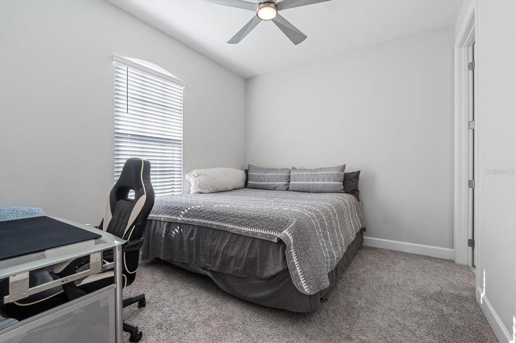 A bedroom features a bed with a gray quilt, a desk, and a ceiling fan — 4512 CRESTPOINT WAY, PALMETTO, FL