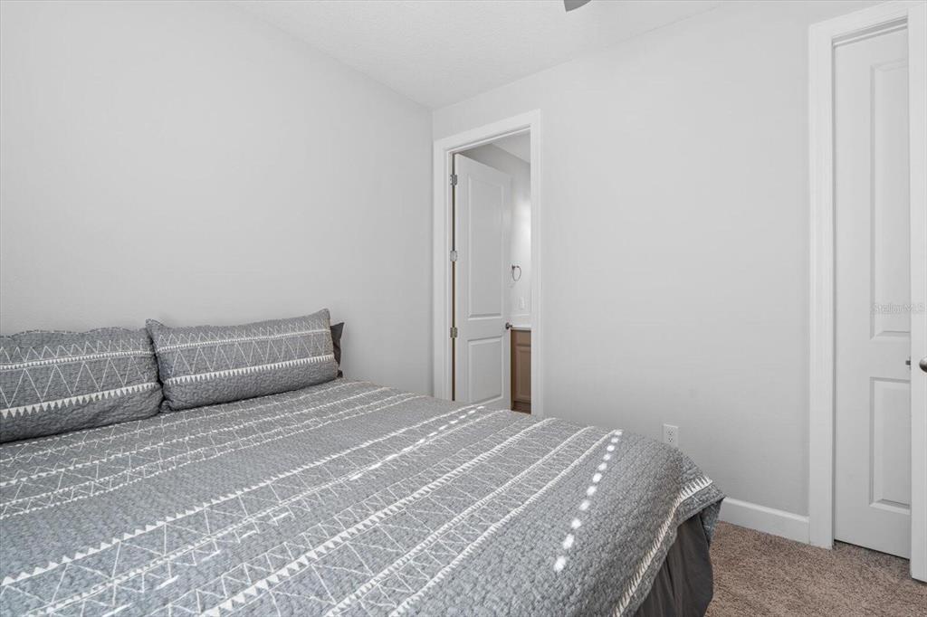 A bedroom with gray walls, a patterned bedspread, and a doorway leading to a bathroom — 4512 CRESTPOINT WAY, PALMETTO, FL