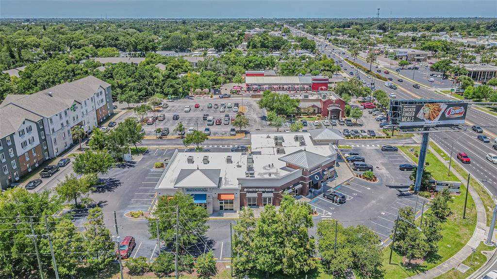 An aerial view shows a commercial strip center with a parking lot and surrounding buildings — 5395 E BAY DRIVE, CLEARWATER, FL