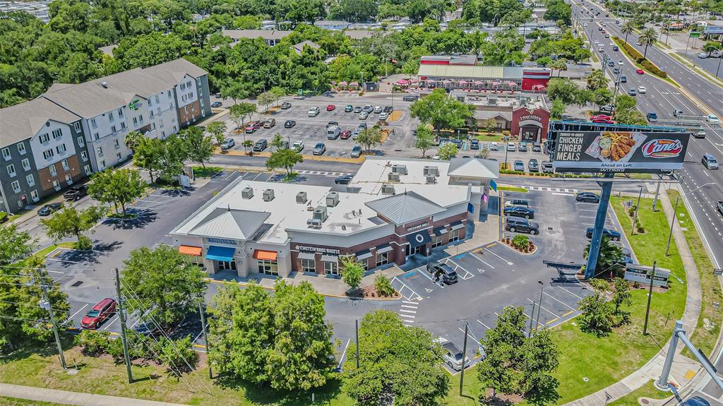 An aerial view shows a commercial plaza with a parking lot and a large billboard — 5395 E BAY DRIVE, CLEARWATER, FL