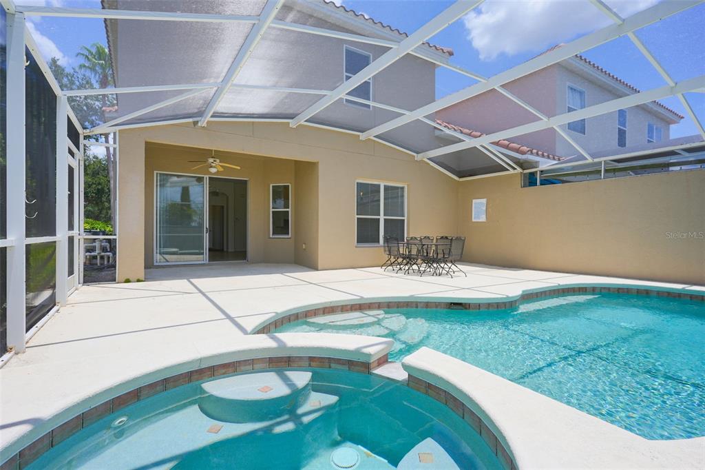 A screened-in patio features a swimming pool, a hot tub, and a dining set — 128 BRUNELLO DRIVE, DAVENPORT, FL