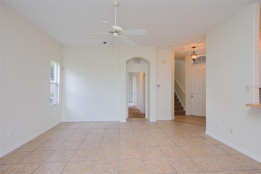 An empty room with beige tile flooring, a ceiling fan, and an arched hallway entrance — 128 BRUNELLO DRIVE, DAVENPORT, FL