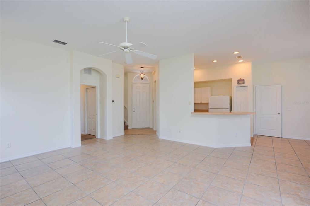 An open-concept living area features light tile flooring, a ceiling fan, and a kitchen pass-through — 128 BRUNELLO DRIVE, DAVENPORT, FL