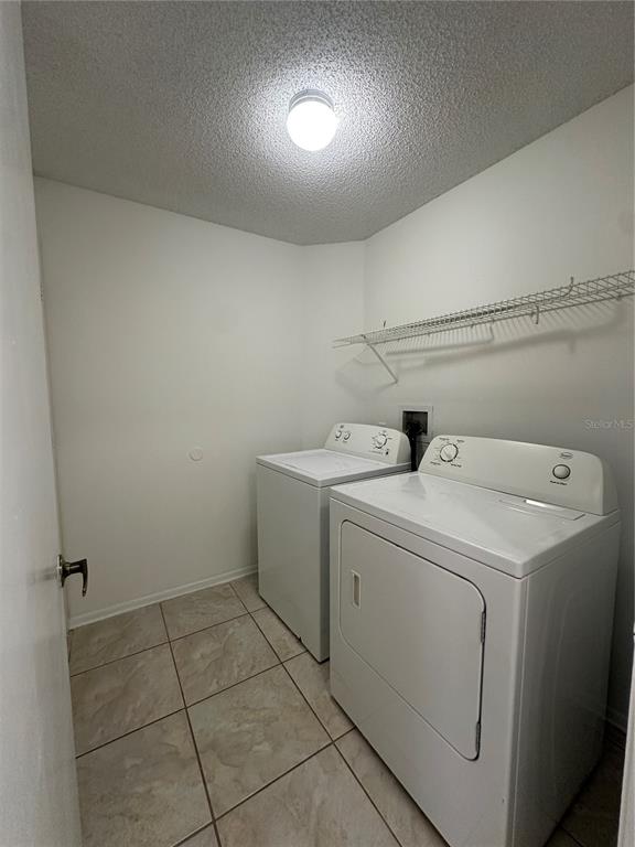 A laundry room with white walls, tiled floors, a washer, a dryer, and wire shelving — 311 DOWNING CIRCLE, DAVENPORT, FL