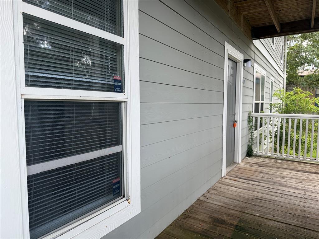 A gray-sided building exterior features a wooden porch, a white-framed window, and a gray door — 2905 SW ARCHER ROAD UNIT 4019, GAINESVILLE, FL