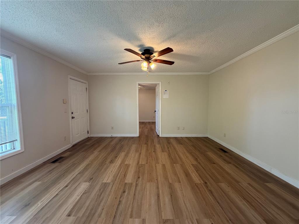 An empty room features light-colored walls, wood-look flooring, a ceiling fan, and a doorway — 2905 SW ARCHER ROAD UNIT 4019, GAINESVILLE, FL