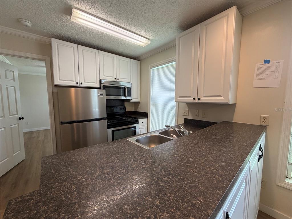 A kitchen features white cabinets, stainless steel appliances, and a dark laminate countertop — 2905 SW ARCHER ROAD UNIT 4019, GAINESVILLE, FL