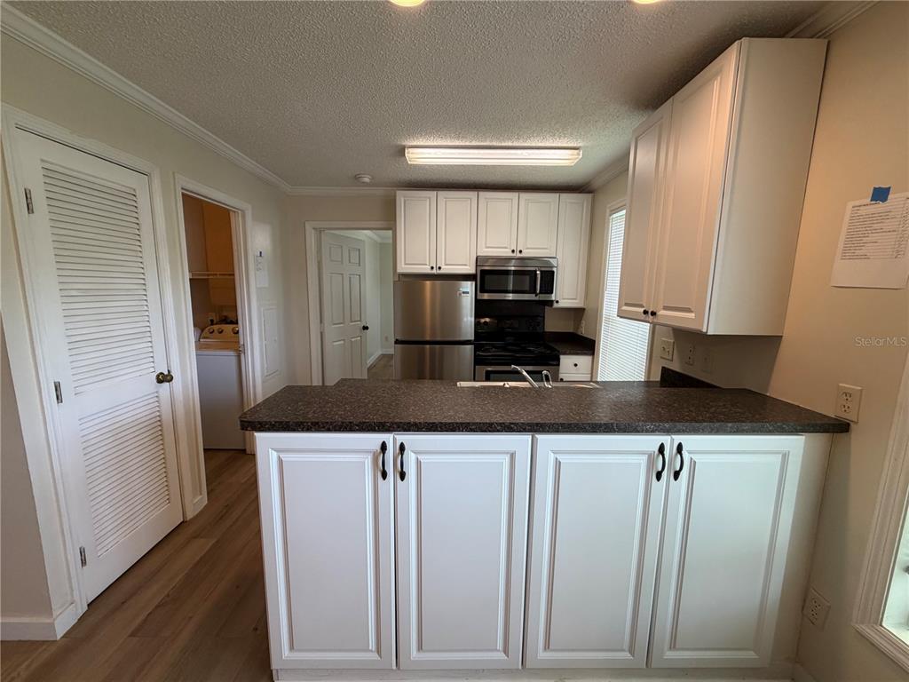 A kitchen features white cabinets, stainless steel appliances, and a dark countertop breakfast bar — 2905 SW ARCHER ROAD UNIT 4019, GAINESVILLE, FL