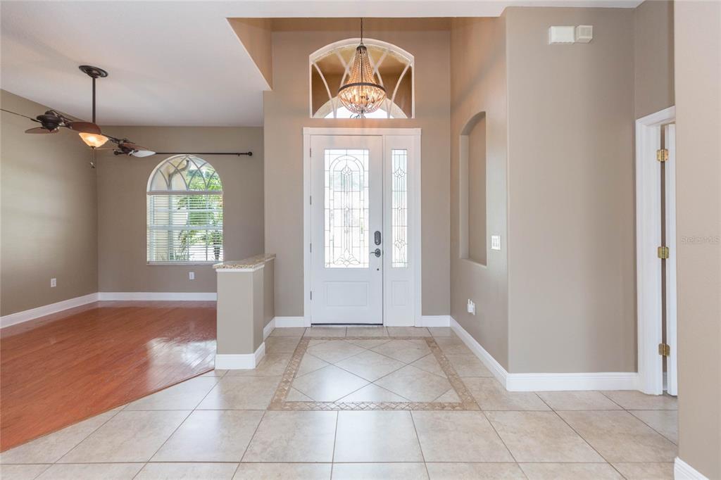 An entryway features a white front door, a chandelier, tile flooring, and an adjacent room — 11544 PINE HOLLOW WAY, DADE CITY, FL