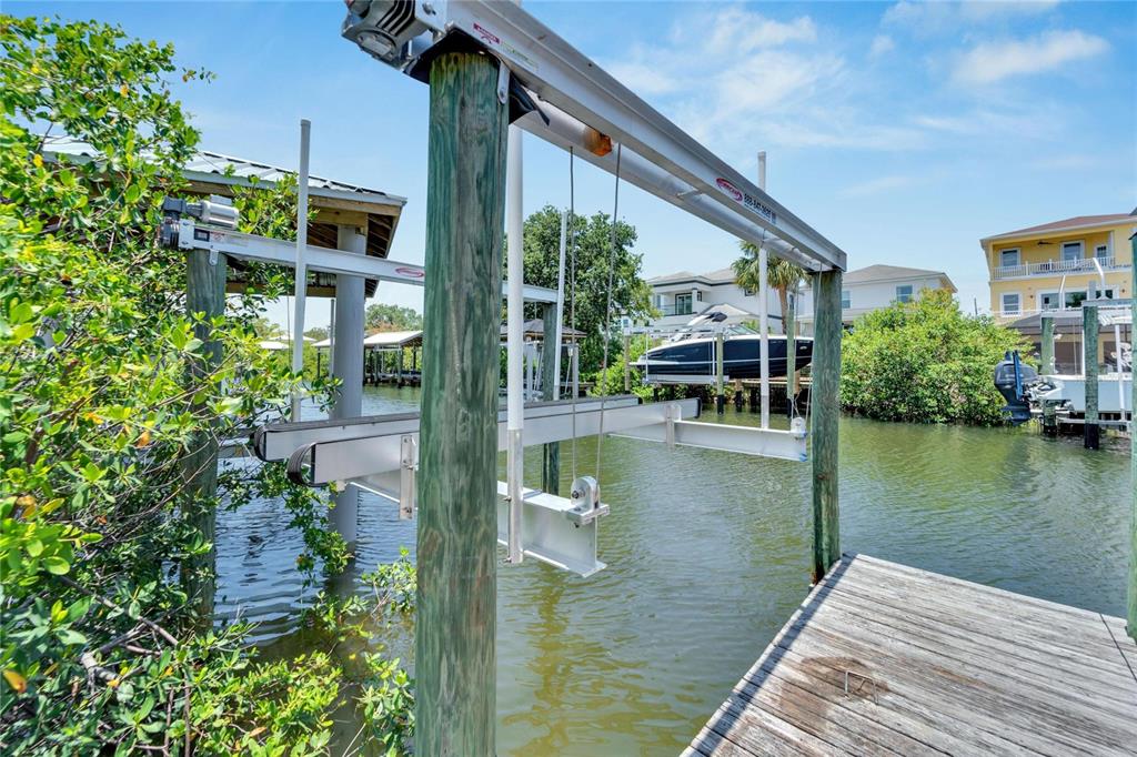 A boat lift structure stands over a canal next to a wooden dock and mangroves — 517 TREVISO DRIVE, APOLLO BEACH, FL