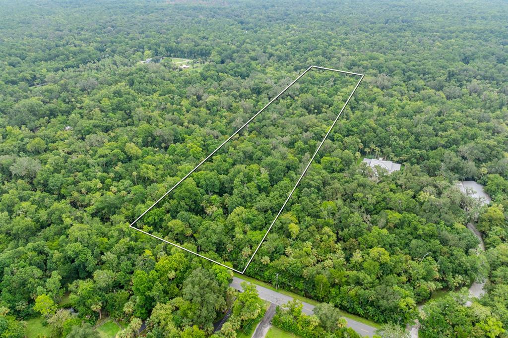 An aerial view shows a rectangular plot of land outlined in white amidst dense forest — STONE STREET, OVIEDO, FL