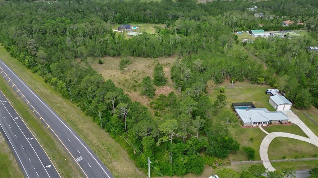 An aerial view shows a wooded lot adjacent to a highway and a residential property — 0 W SR 40 HIGHWAY, ORMOND BEACH, FL