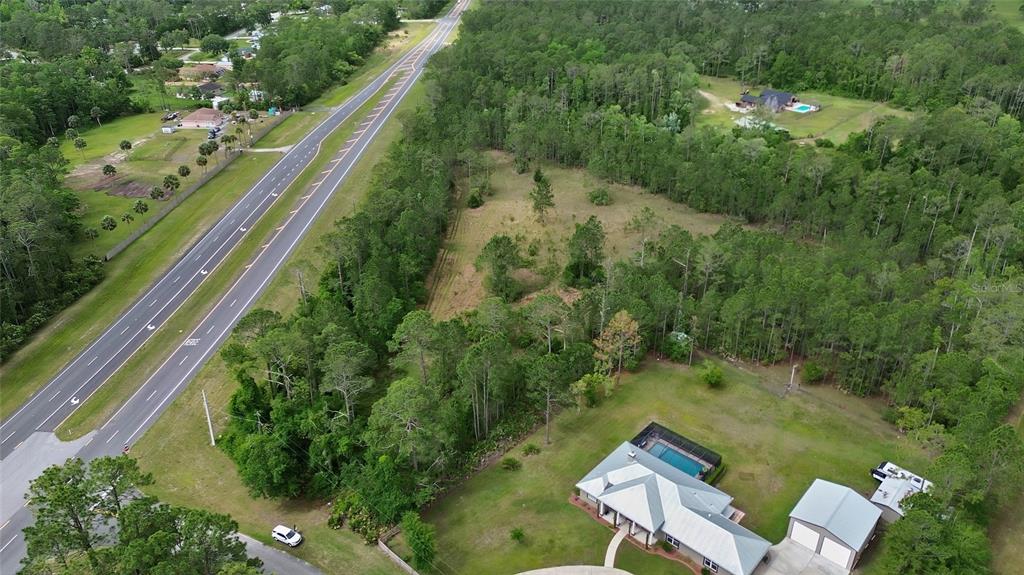 An aerial view shows a house with a pool next to a road and forest — 0 W SR 40 HIGHWAY, ORMOND BEACH, FL