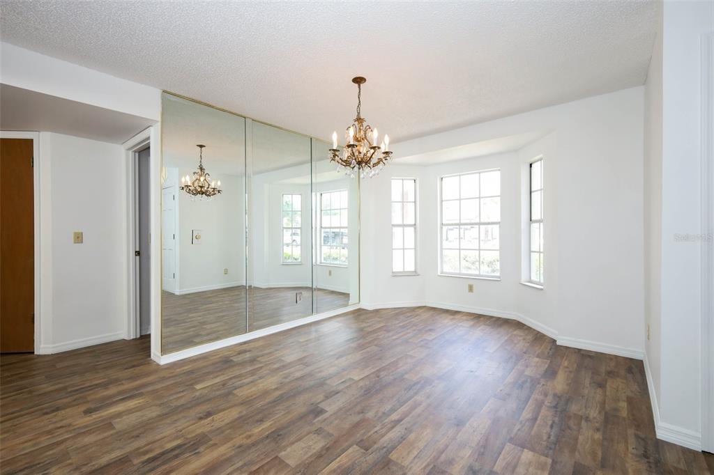 A dining room with wood-look flooring, a crystal chandelier, and a large mirrored wall — 1675 THORNHILL CIRCLE, OVIEDO, FL