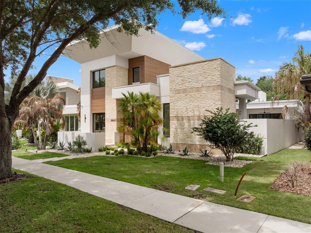 A modern entryway features a large wooden pivot door opening to an outdoor patio area — 8643 FARTHINGTON WAY, ORLANDO, FL