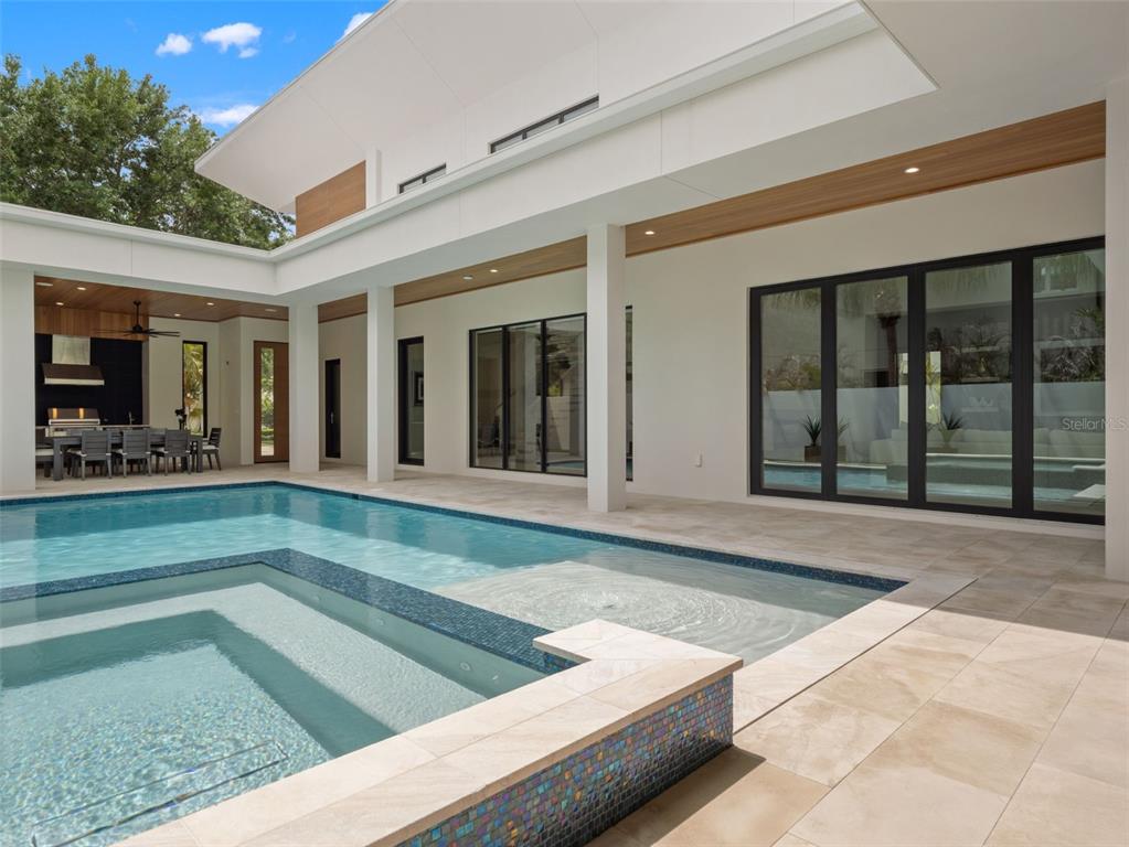 A modern house exterior features a rectangular swimming pool with an attached spa and patio — 8643 FARTHINGTON WAY, ORLANDO, FL