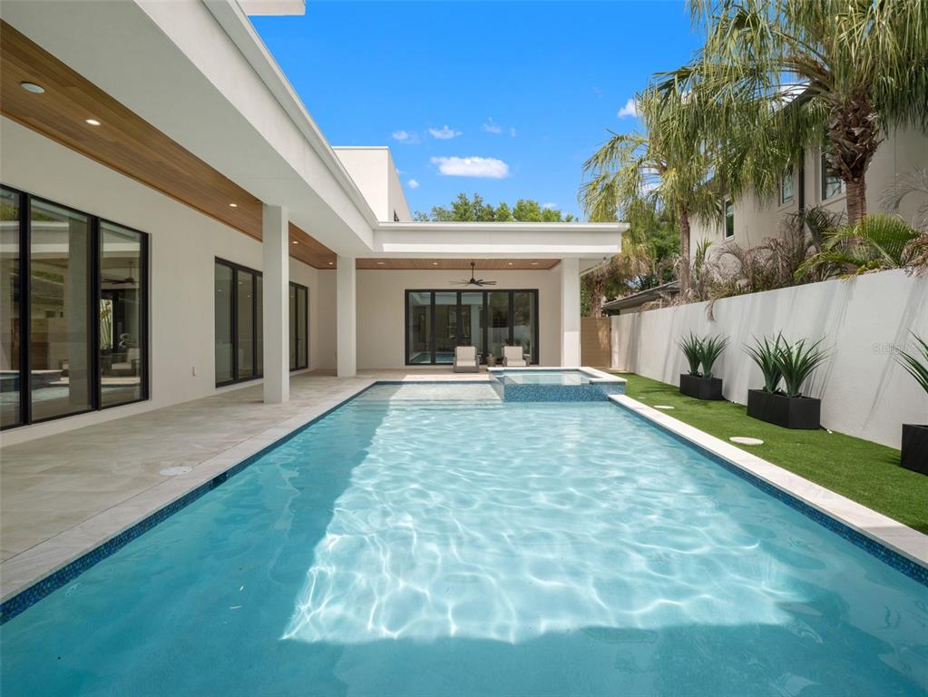 A modern home exterior features a swimming pool, a spa, and a covered patio area — 8643 FARTHINGTON WAY, ORLANDO, FL