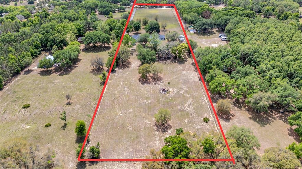 An aerial view shows a large, trapezoidal plot of land outlined in red with trees — 12305 HOWEY CROSS ROAD, CLERMONT, FL