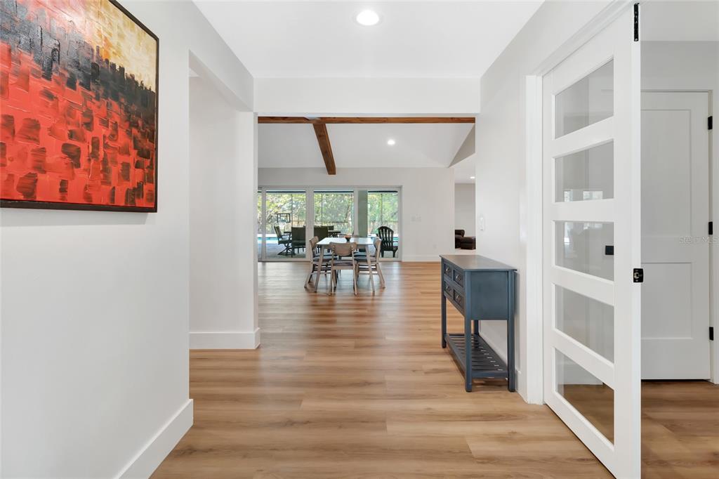 A bright hallway with wood-look flooring leads to a dining area with a vaulted ceiling — 12305 HOWEY CROSS ROAD, CLERMONT, FL