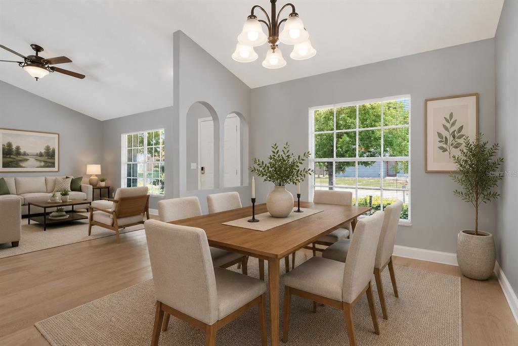 A dining room with a wooden table, light-colored chairs, and a chandelier near a living area — 2608 BERRYVINE PLACE, VALRICO, FL
