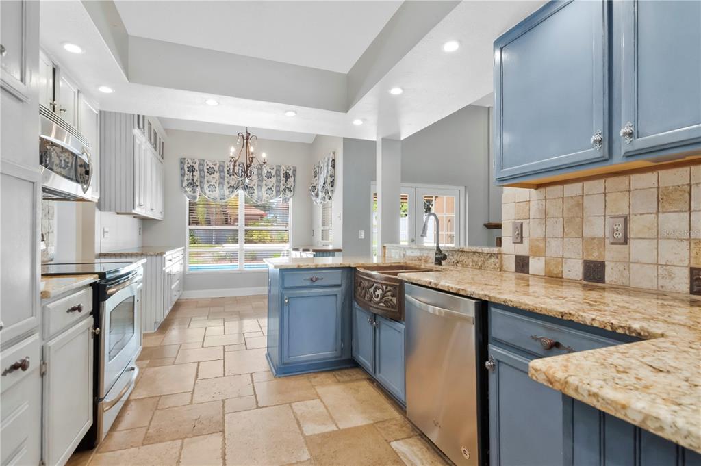 A kitchen features blue and white cabinets, granite countertops, a farmhouse sink, and tile flooring — 2608 BERRYVINE PLACE, VALRICO, FL